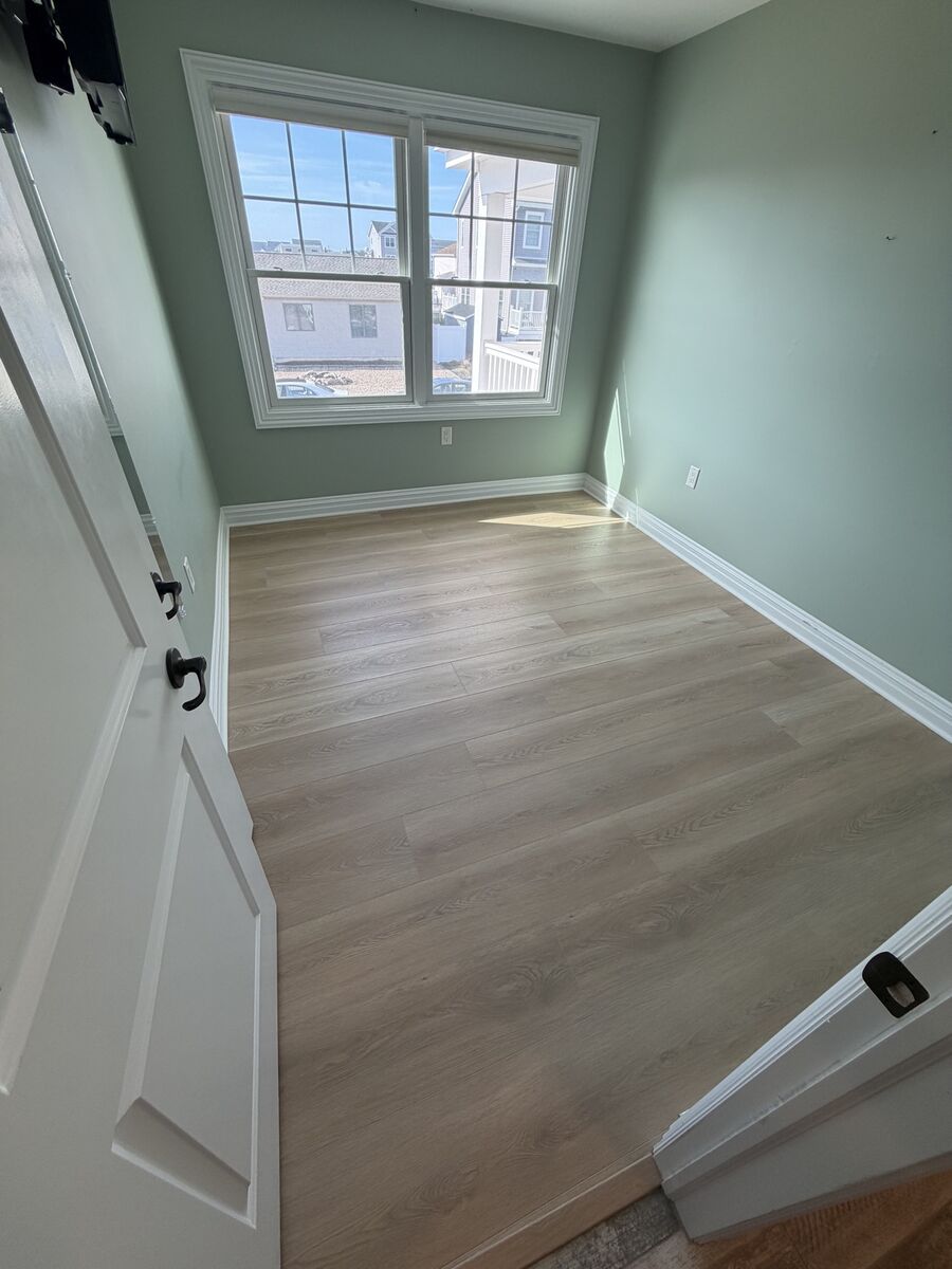 Bedroom with sage accent wall and finished hardwood floor