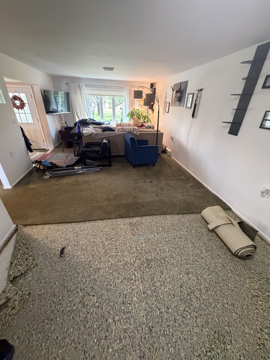 Old carpet torn out and rolled up, subfloor exposed and ready for prep
