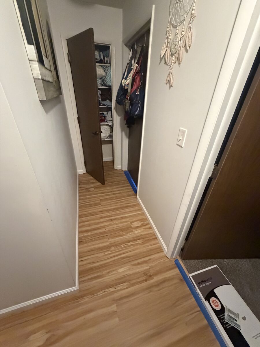 Hallway leading into a bedroom, both with matching finished flooring
