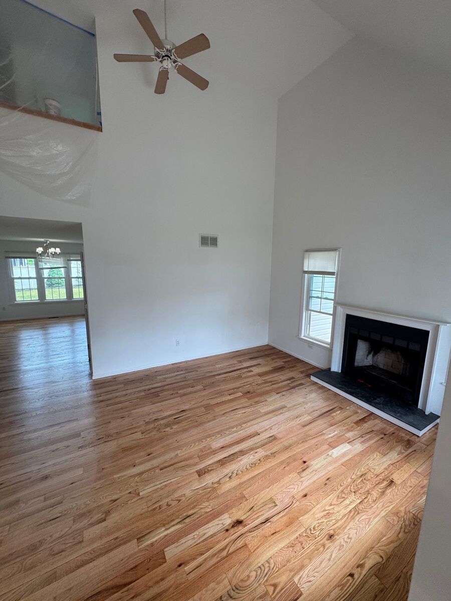 Newly refinished hardwood floor in a vaulted living room with a fireplace, an Oak Flooring install